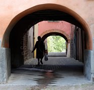 Anziana che cammina sotto le volte di una antica strada