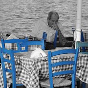 Tavolino con tovaglia a scacchi, sedie azzurre e signore anziano